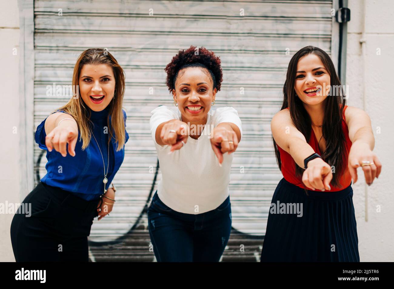 Happy women pointing in front of closed shutter Stock Photo