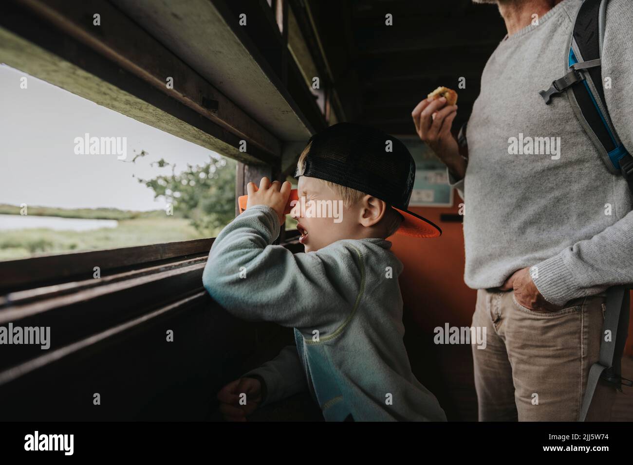 Boy wearing cap looking through binoculars Stock Photo
