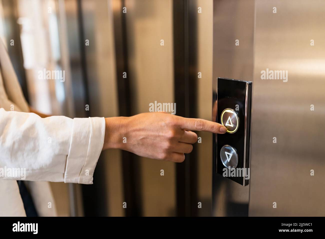 Hand of businesswoman pushing elevator button Stock Photo