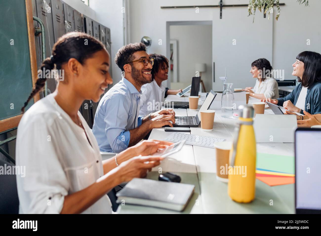 Happy multiracial business colleagues working at desk in coworking ...