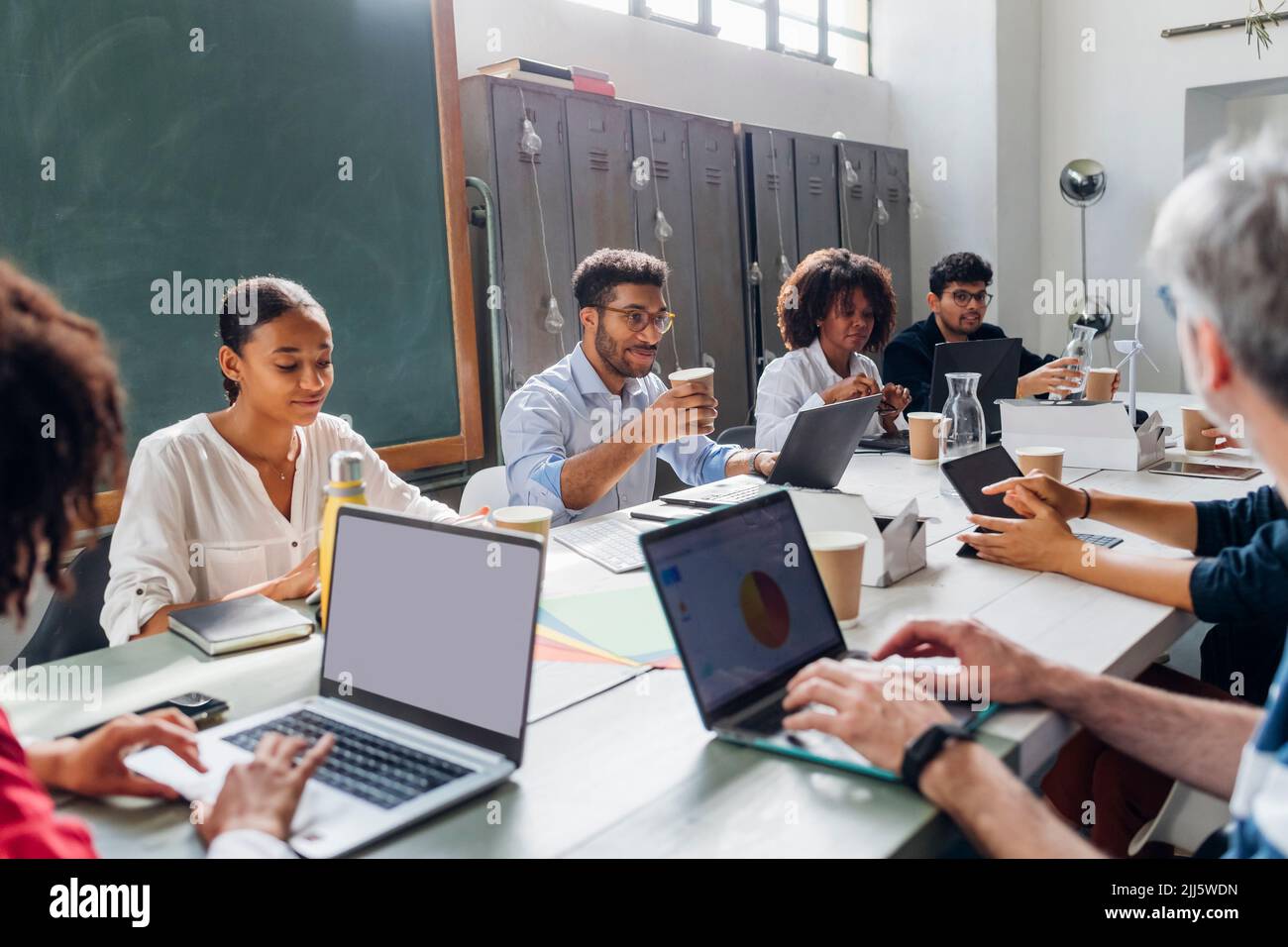 Multiracial business colleagues working together at desk in office ...