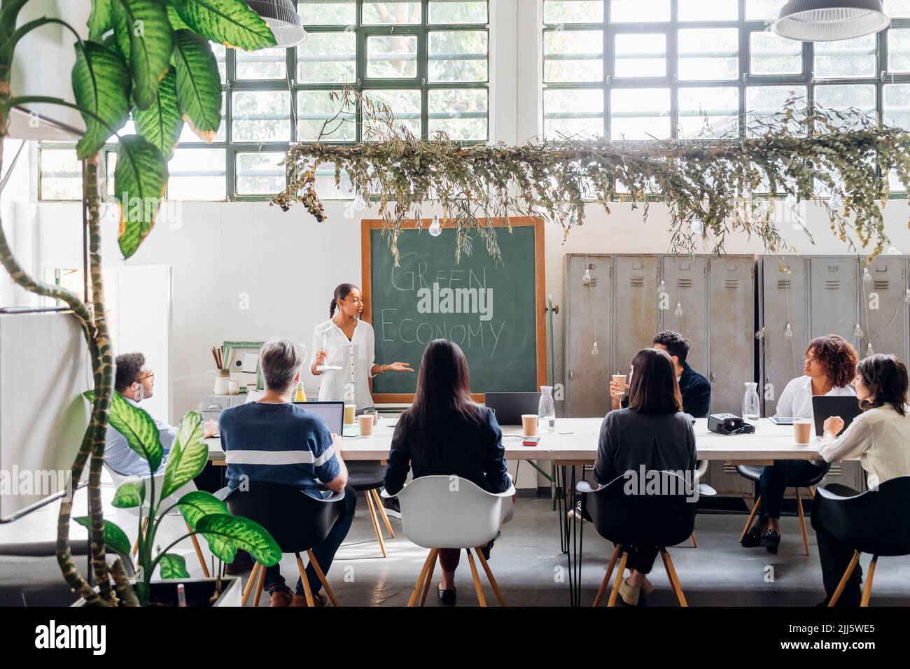 Businesswoman explaining about wind turbine to colleagues in coworking space Stock Photo