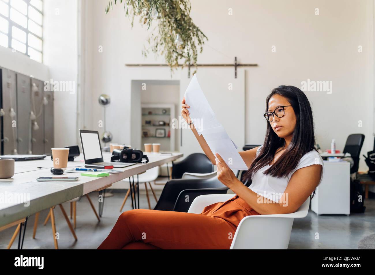 Young businesswoman reading paper documents in office Stock Photo