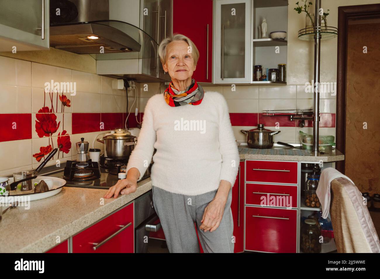 Smiling senior woman standing by kitchen counter Stock Photo