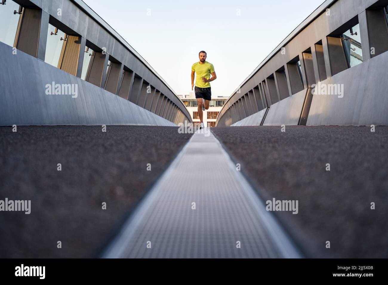Young man jogging on footbridge Stock Photo