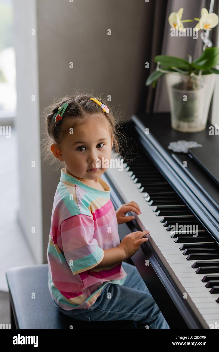 Cute little girl playing piano at a music school. Preschool child