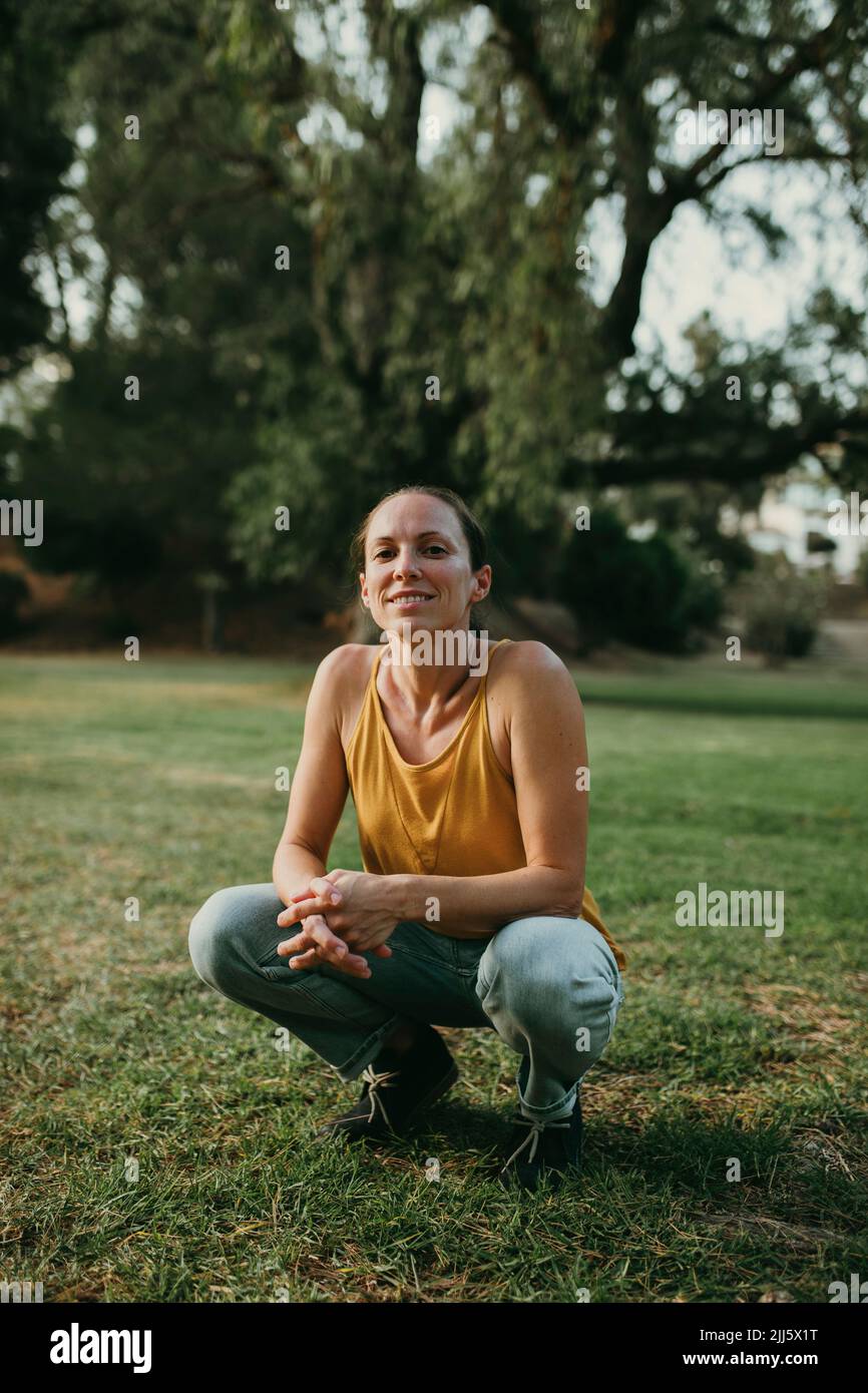Smiling woman crouching at park Stock Photo