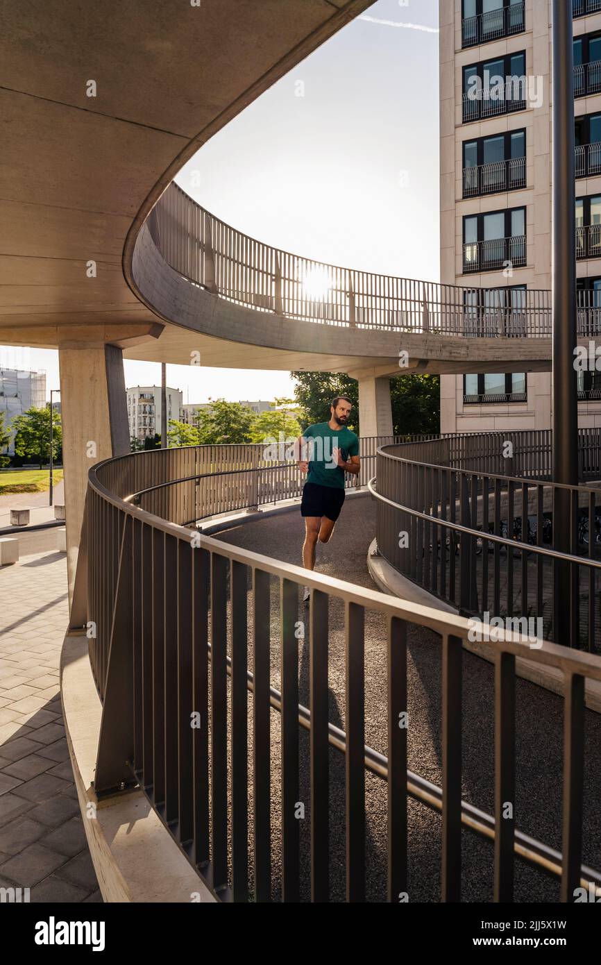 Young man jogging on footbridge Stock Photo