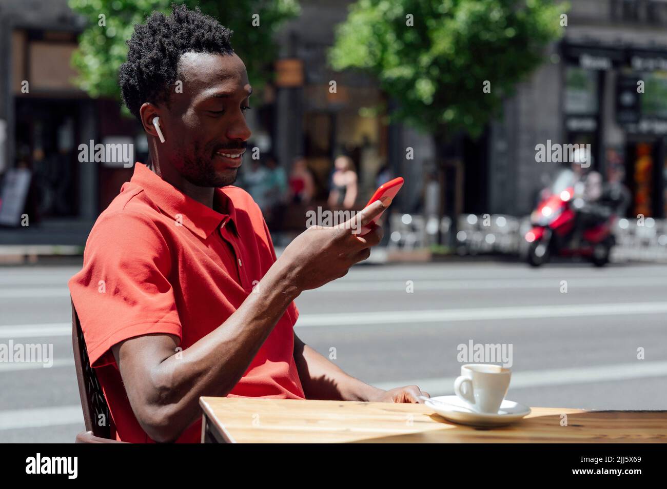 Smiling man using mobile phone sitting at cafe Stock Photo