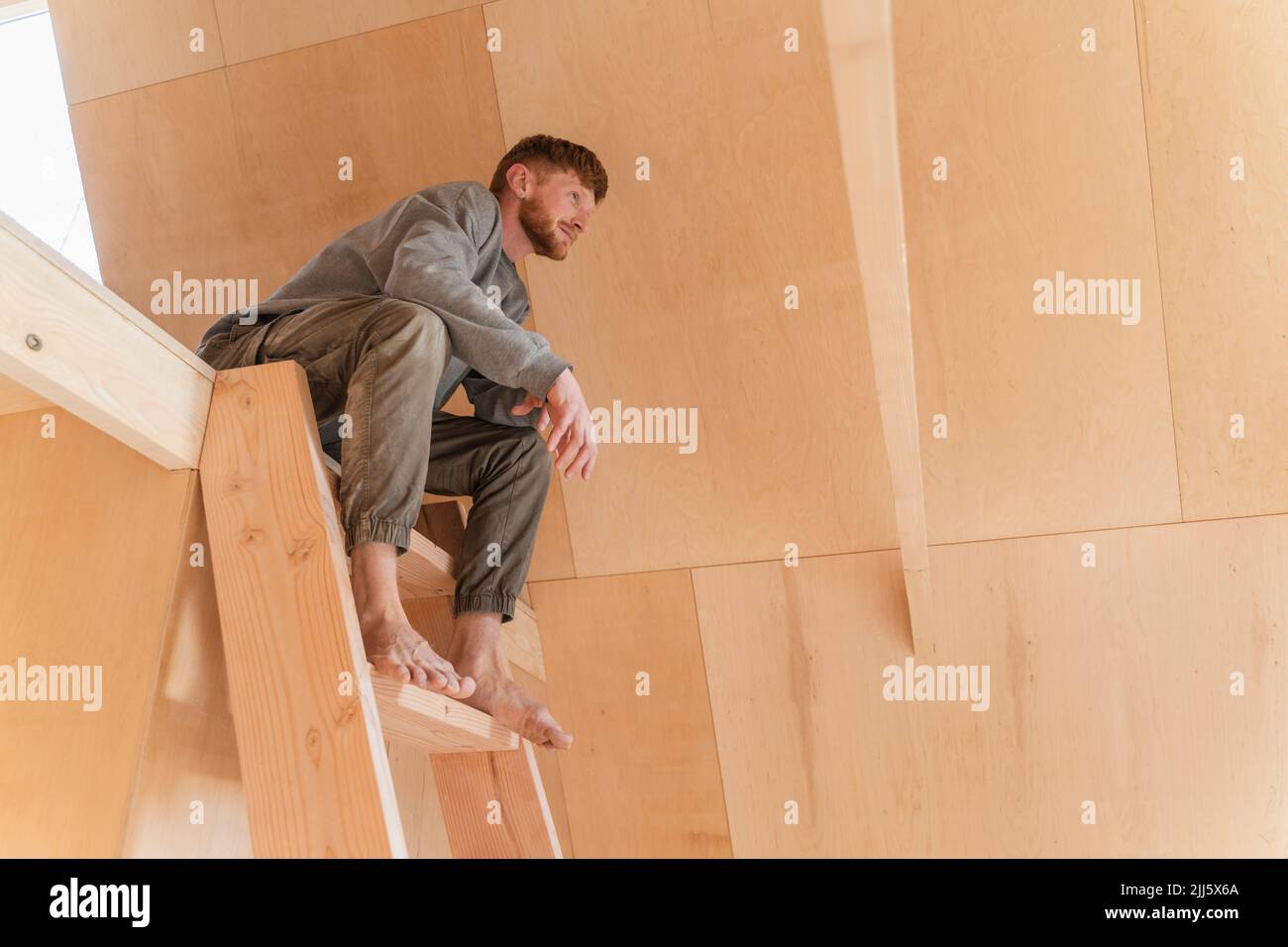Man is sitiing on the second floor ladder in eco house Stock Photo - Alamy