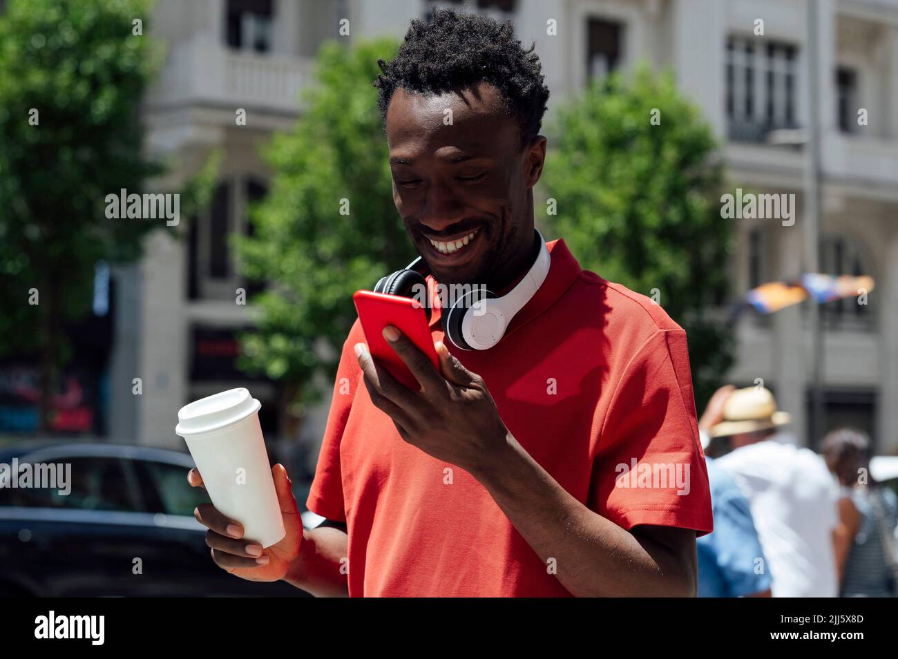 Smiling man with coffee cup using mobile phone Stock Photo