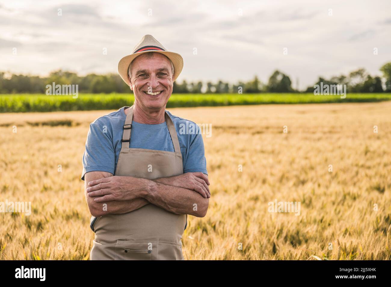 Happy farmer wearing apron standing with arms crossed in farm Stock ...