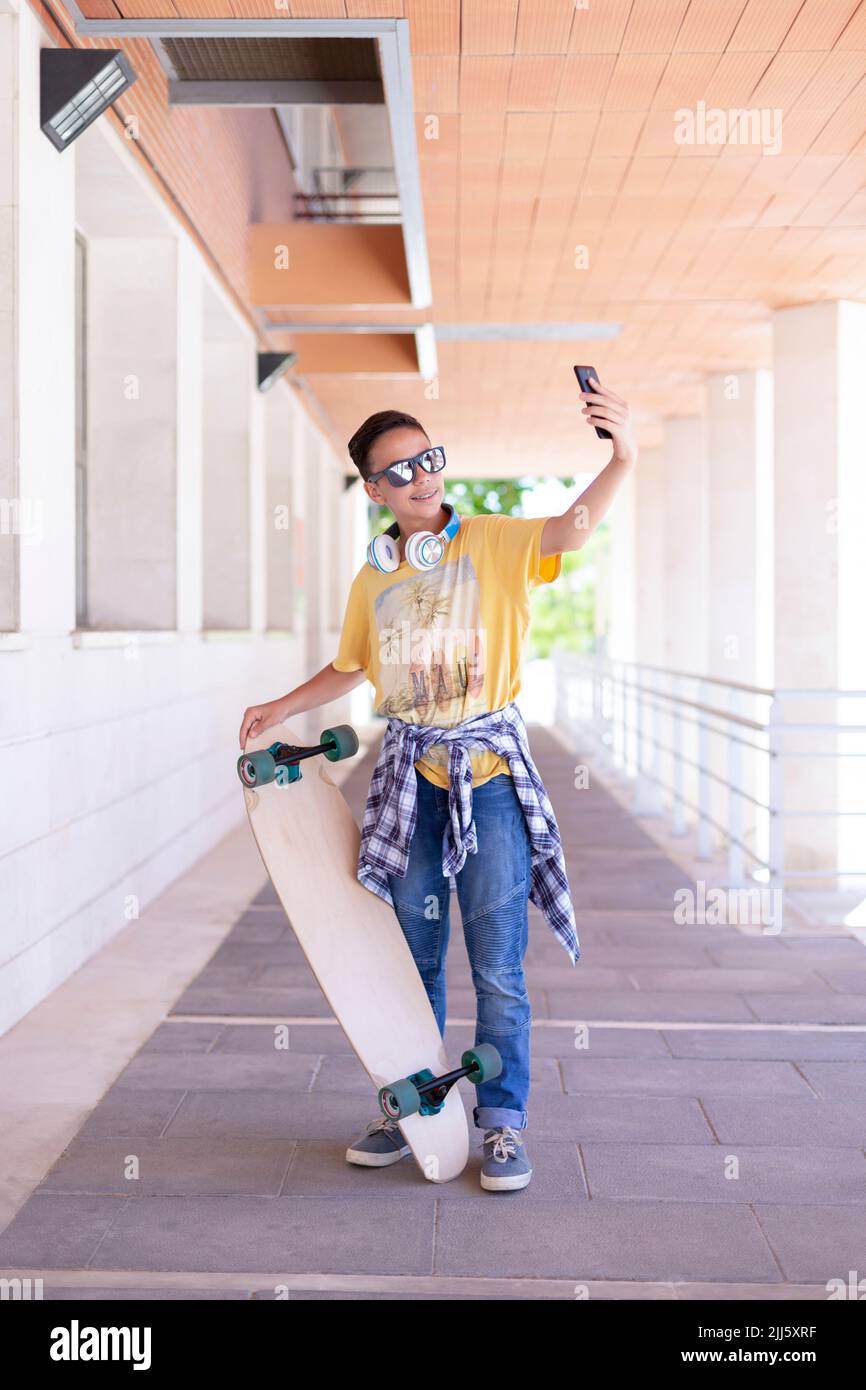 Smiling teenage skateboarder boy taking a picture of himself with his ...