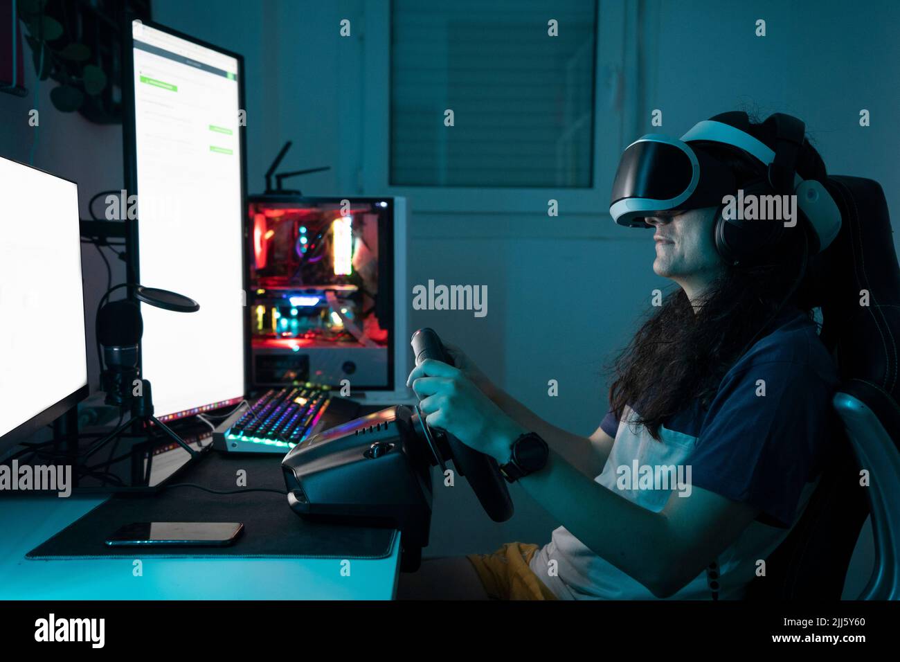 Man wearing VR glasses using steering wheel sitting at home Stock Photo