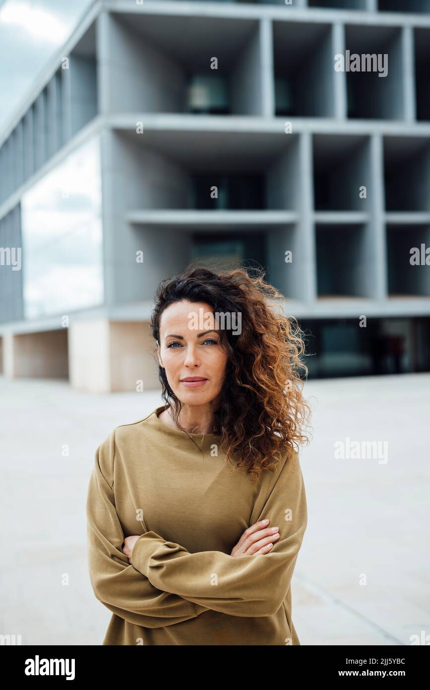 Confident businesswoman with arms crossed standing in front of office building Stock Photo