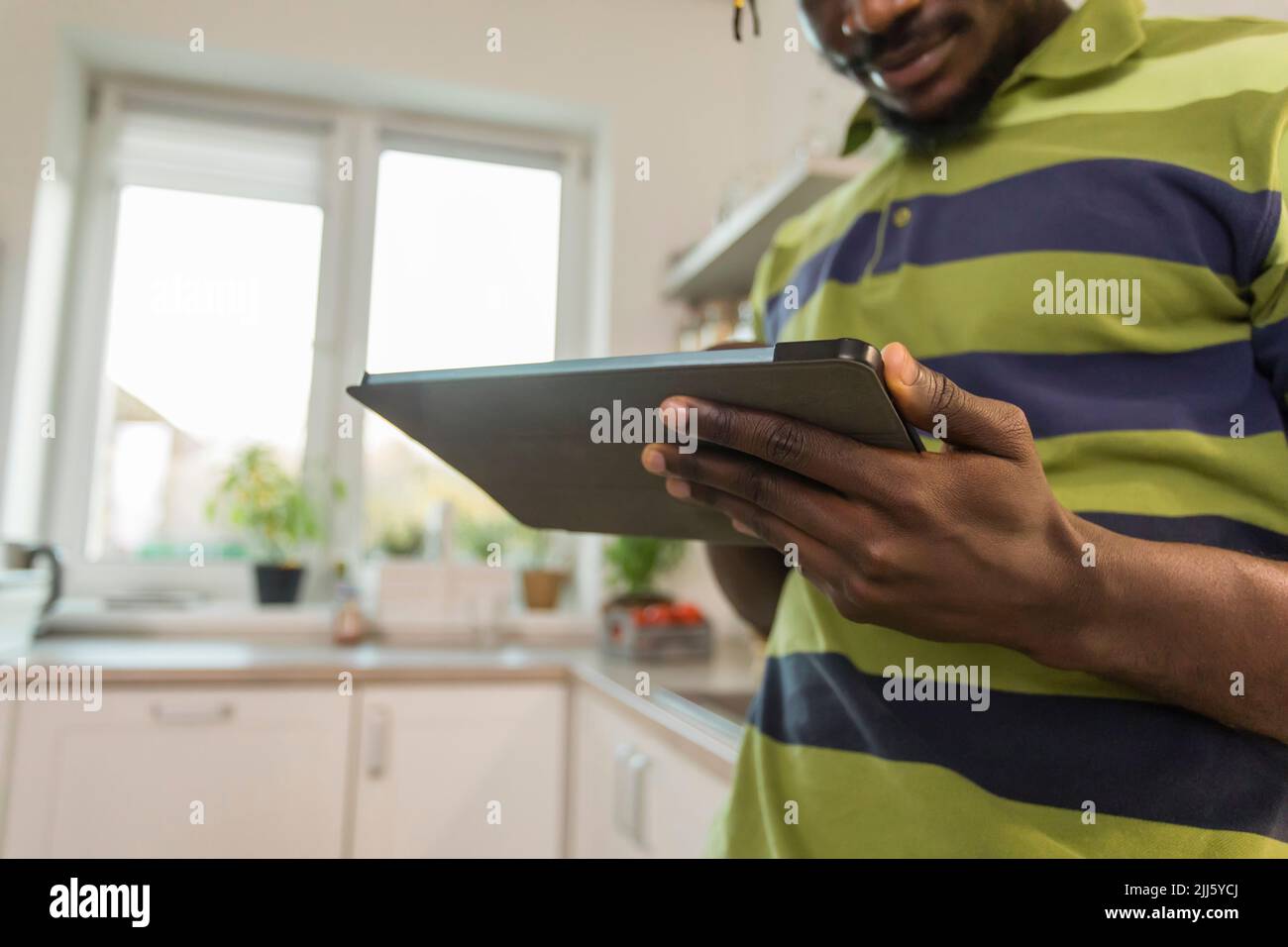 Hands of man using tablet PC in kitchen Stock Photo