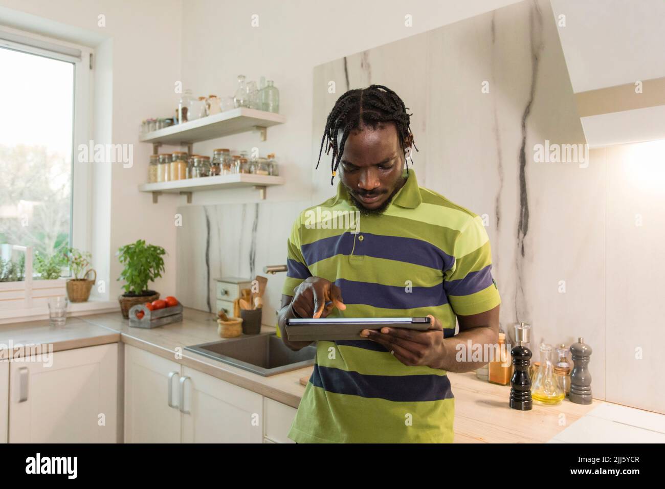 Man using tablet PC in kitchen Stock Photo