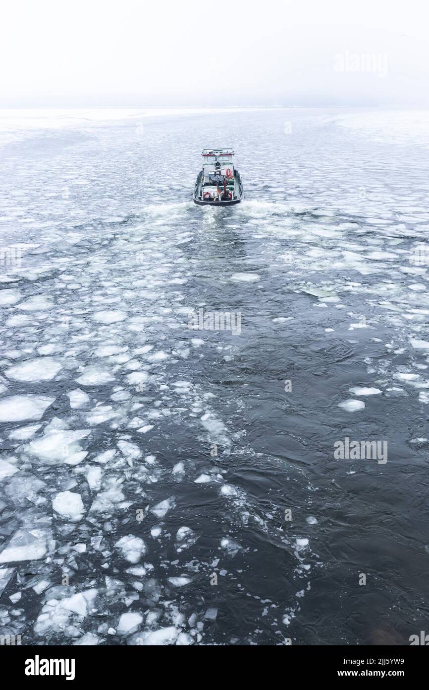 Ice-breaker boat sailing through ice floating in river Havel Stock Photo