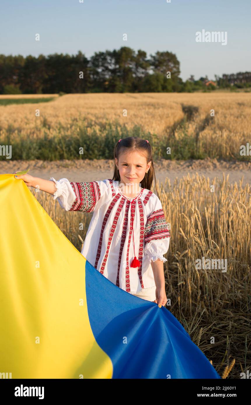 Ukrainian girl in a traditional embroidered shirt with a yellow and blue Ukrainian flag in the foreground. attracting attention to support Ukrainians Stock Photo