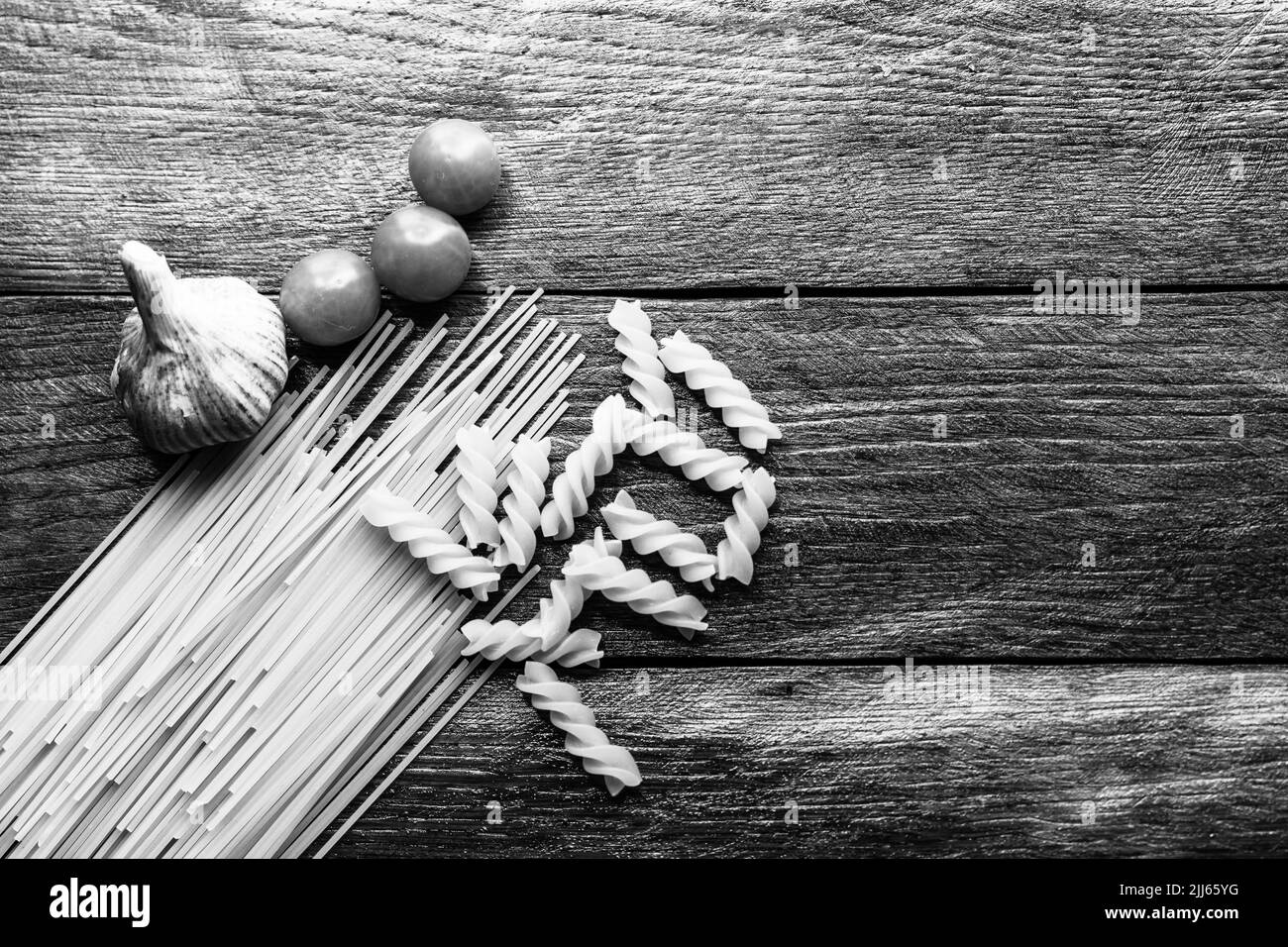 Spaghetti, cherry tomatoes and garlic on a wooden board. Stock Photo