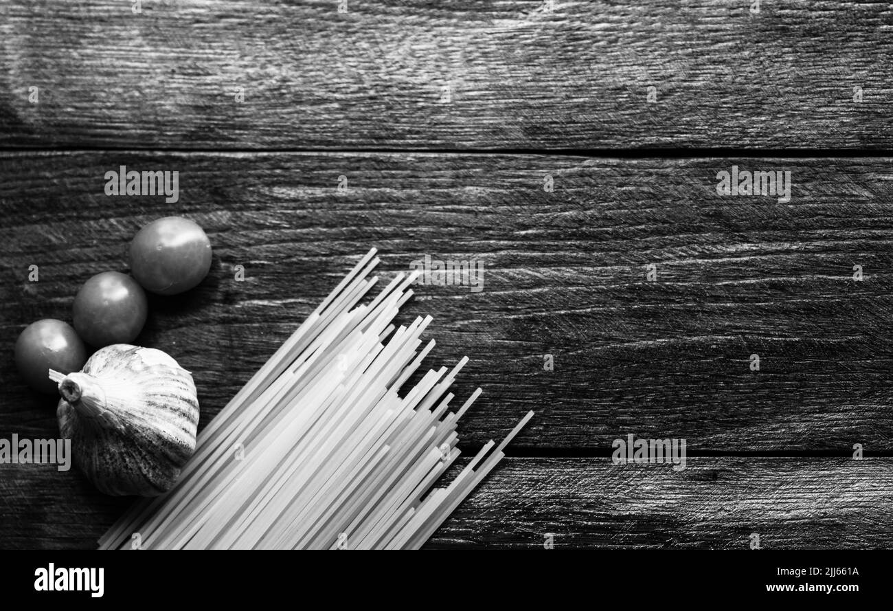 Spaghetti, cherry tomatoes and garlic on a wooden board. Stock Photo