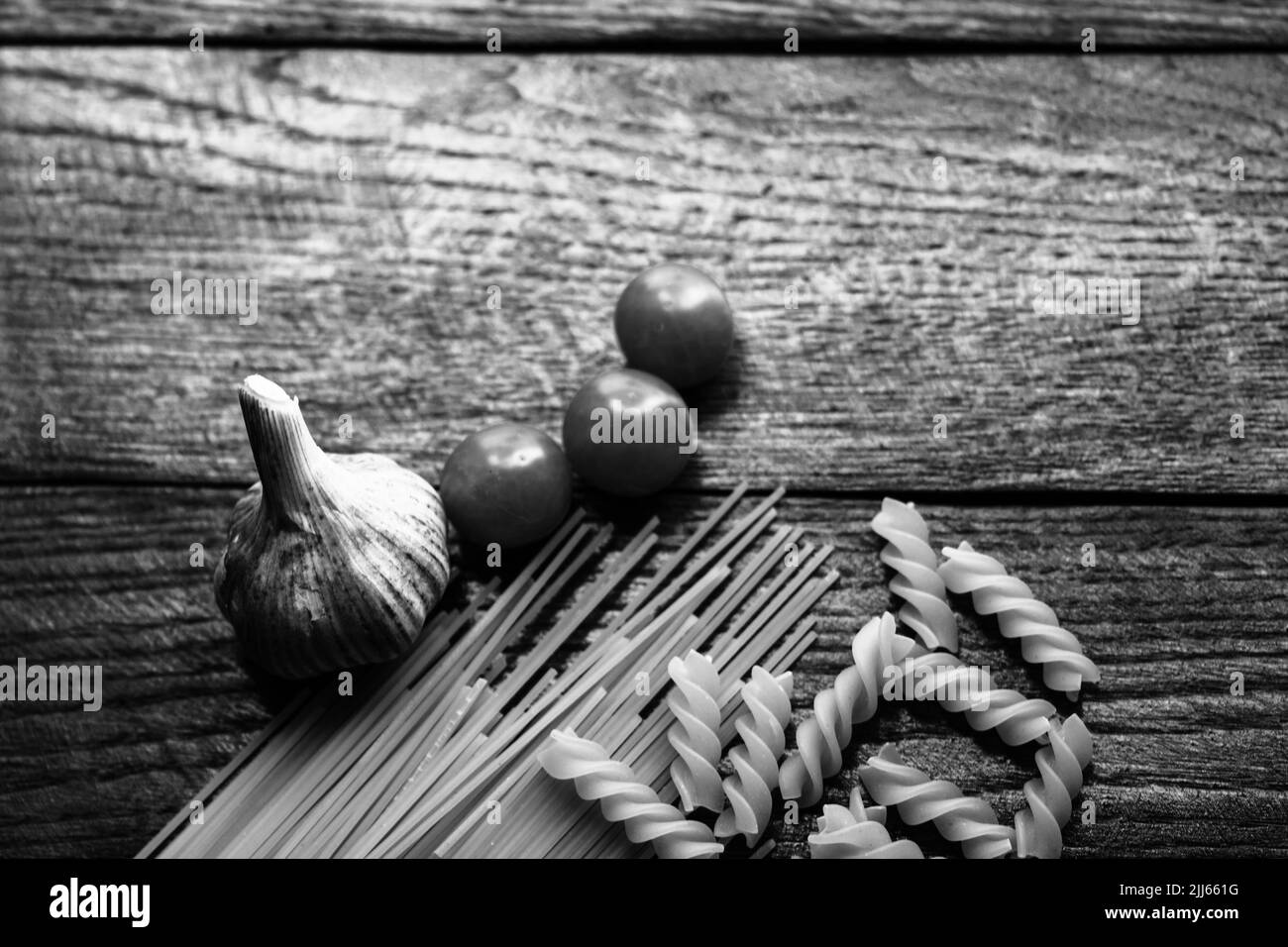 Spaghetti, cherry tomatoes and garlic on a wooden board. Stock Photo