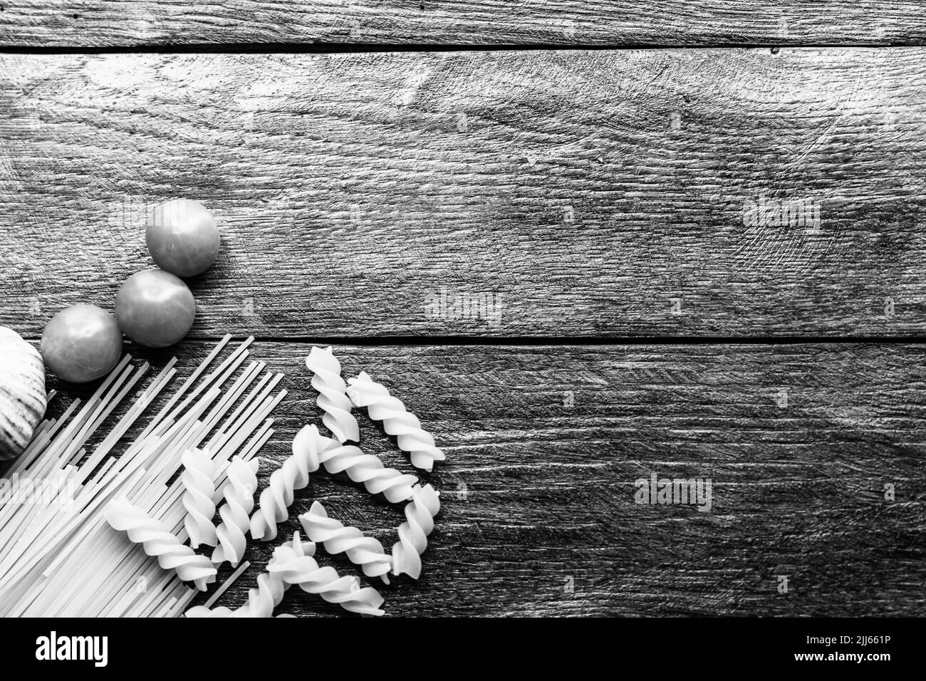 Spaghetti, cherry tomatoes and garlic on a wooden board. Stock Photo