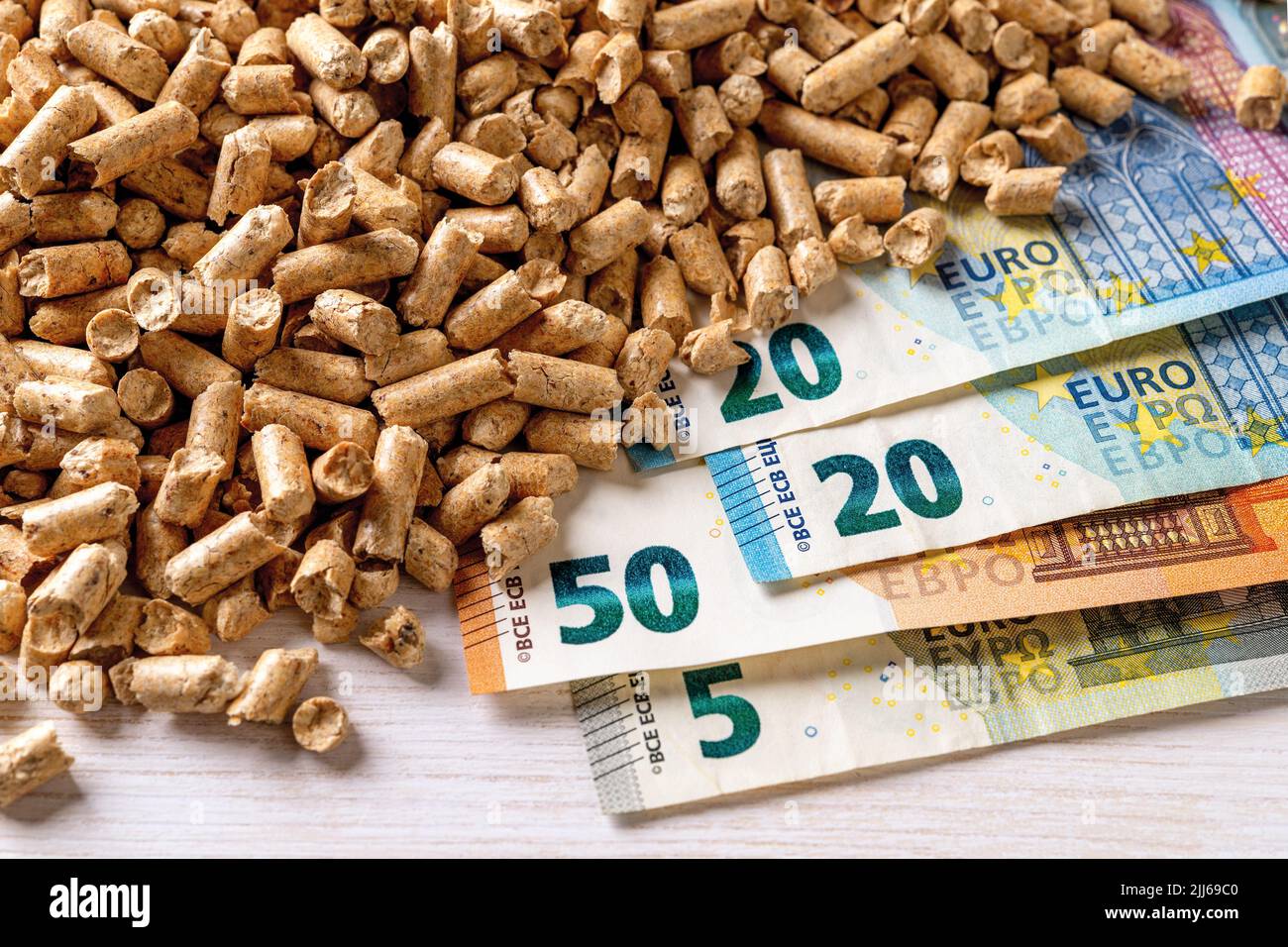 Heap of wood pellets and euro paper banknotes top view. Costs of organic biofuel from compressed sawdust. Ecological heating, alternative energy. Stock Photo