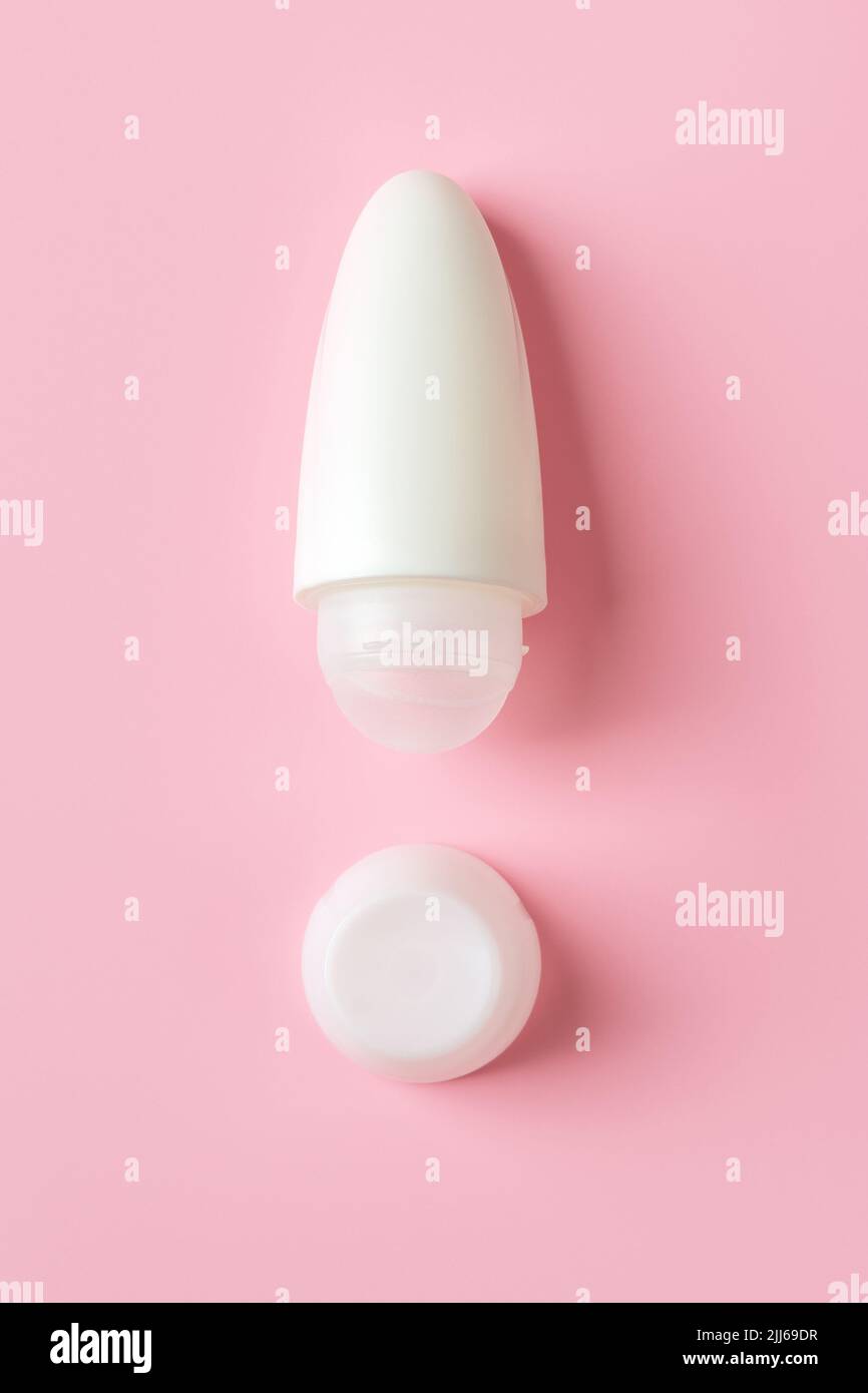 Roll on antiperspirant as the exclamation point shape on a pink background. Roll-on body deodorant in a white plastic tube. Hygiene and toiletries. Stock Photo