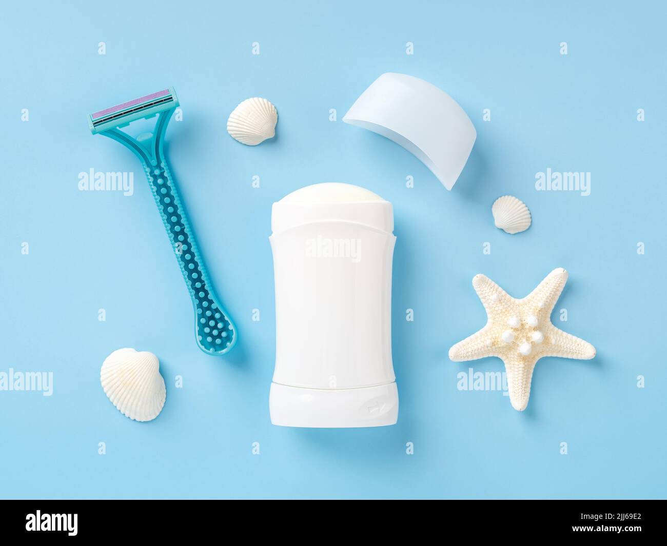 Solid antiperspirant deodorant, disposable shaving razor, sea star and shells against blue background. Purity and personal hygiene items concept. Stock Photo