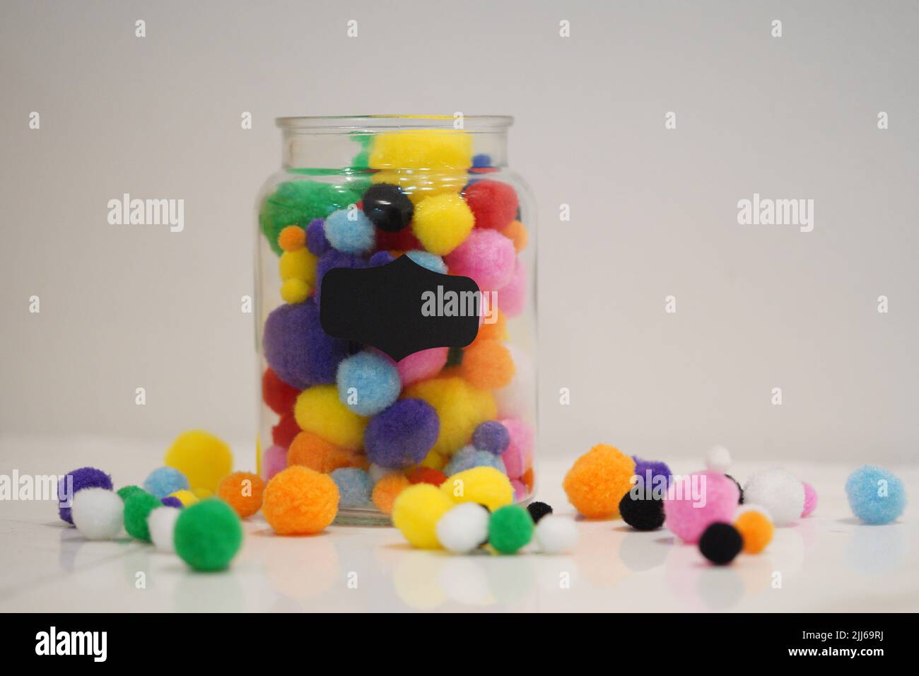 Colourful pom pom on a jar with background space for text. Background