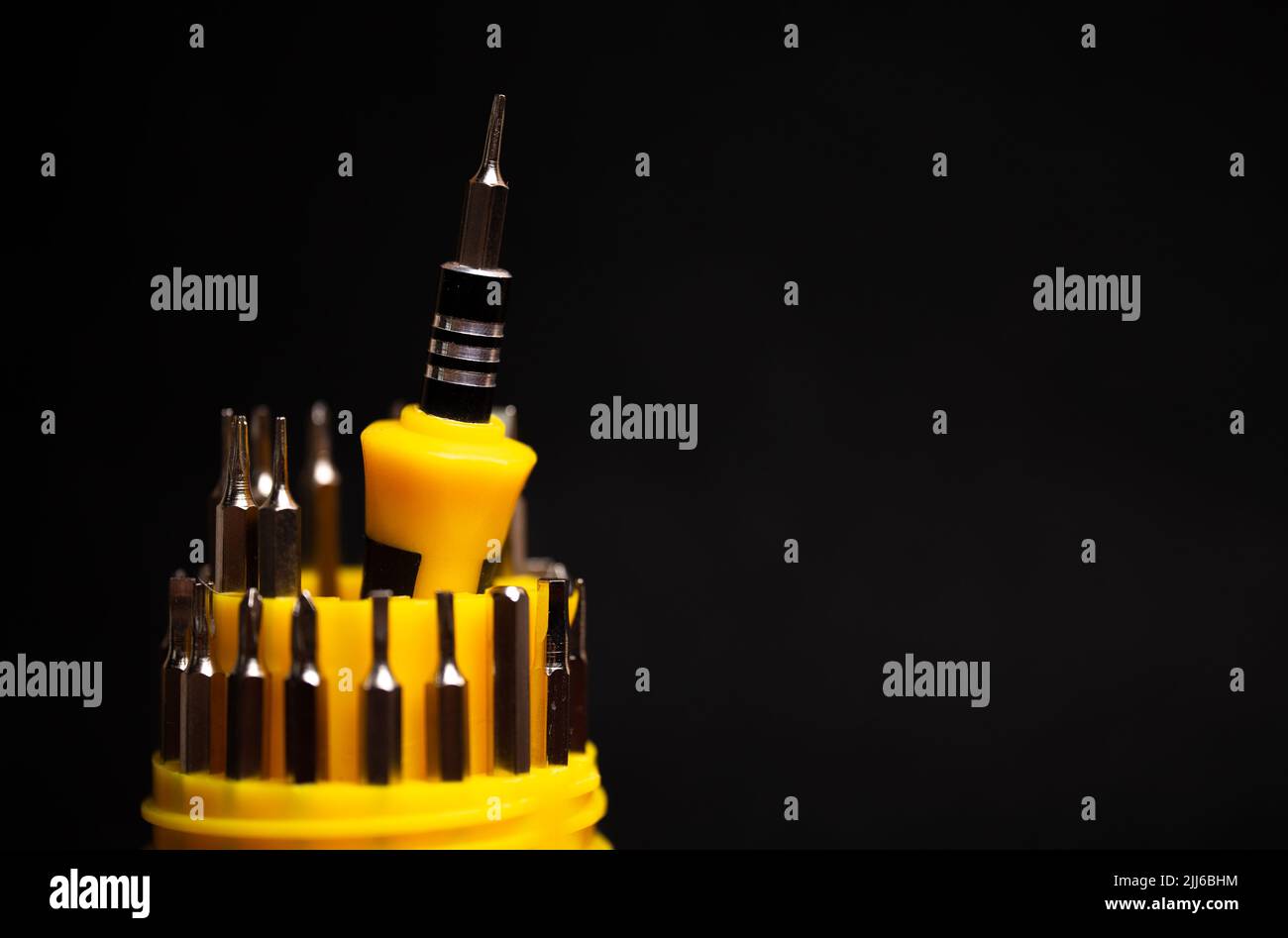 yellow multifunctional set of small screwdrivers on a black background. Stock Photo