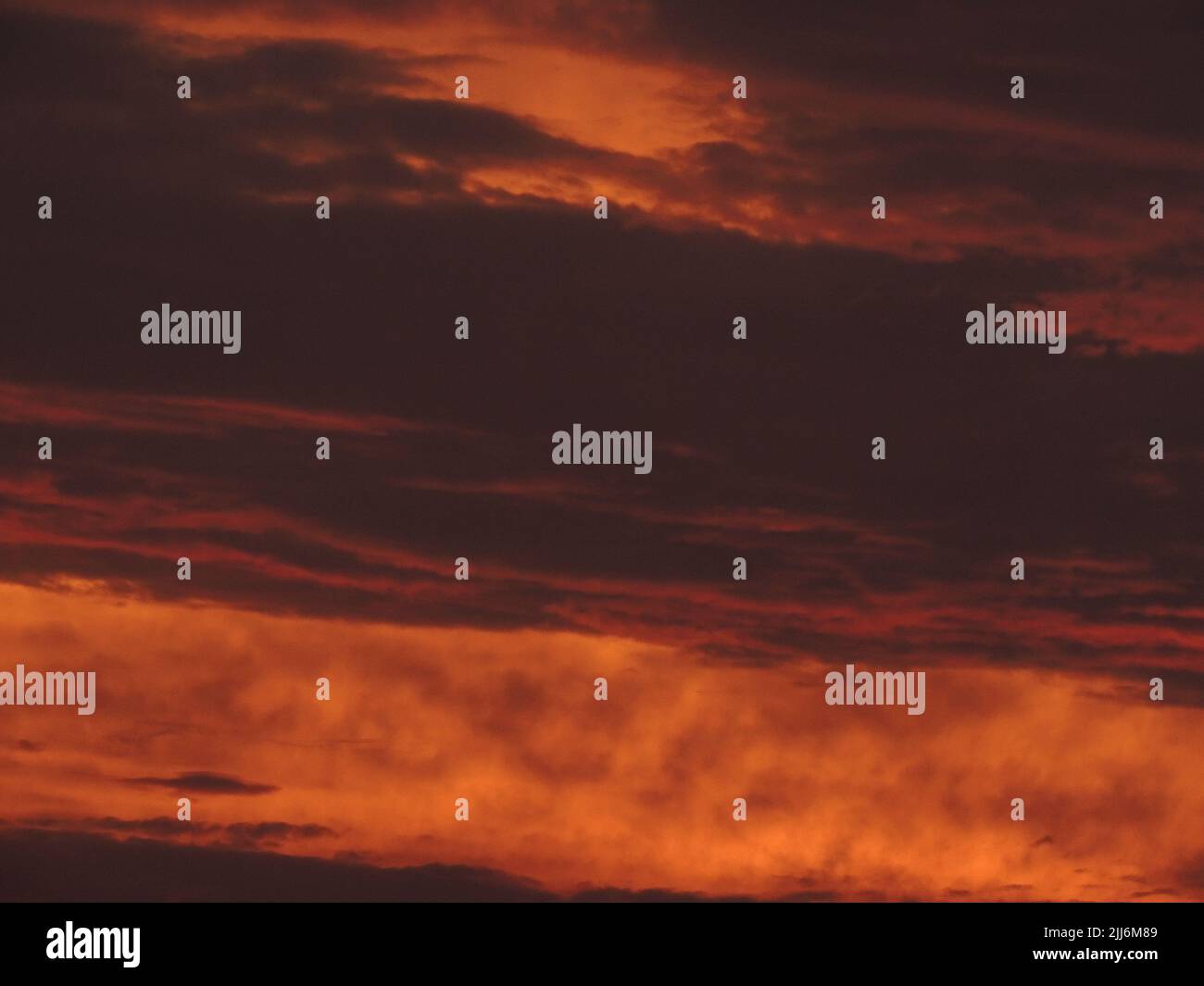 A fiery orange sunset sky background with dark clouds Stock Photo - Alamy