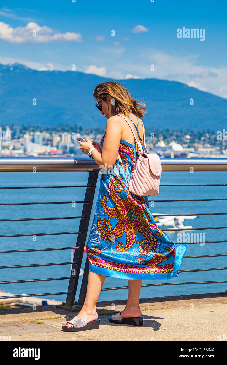 Attractive woman checking her phone overlooking the Vancouver waterfront in British Columbia, Canada Stock Photo