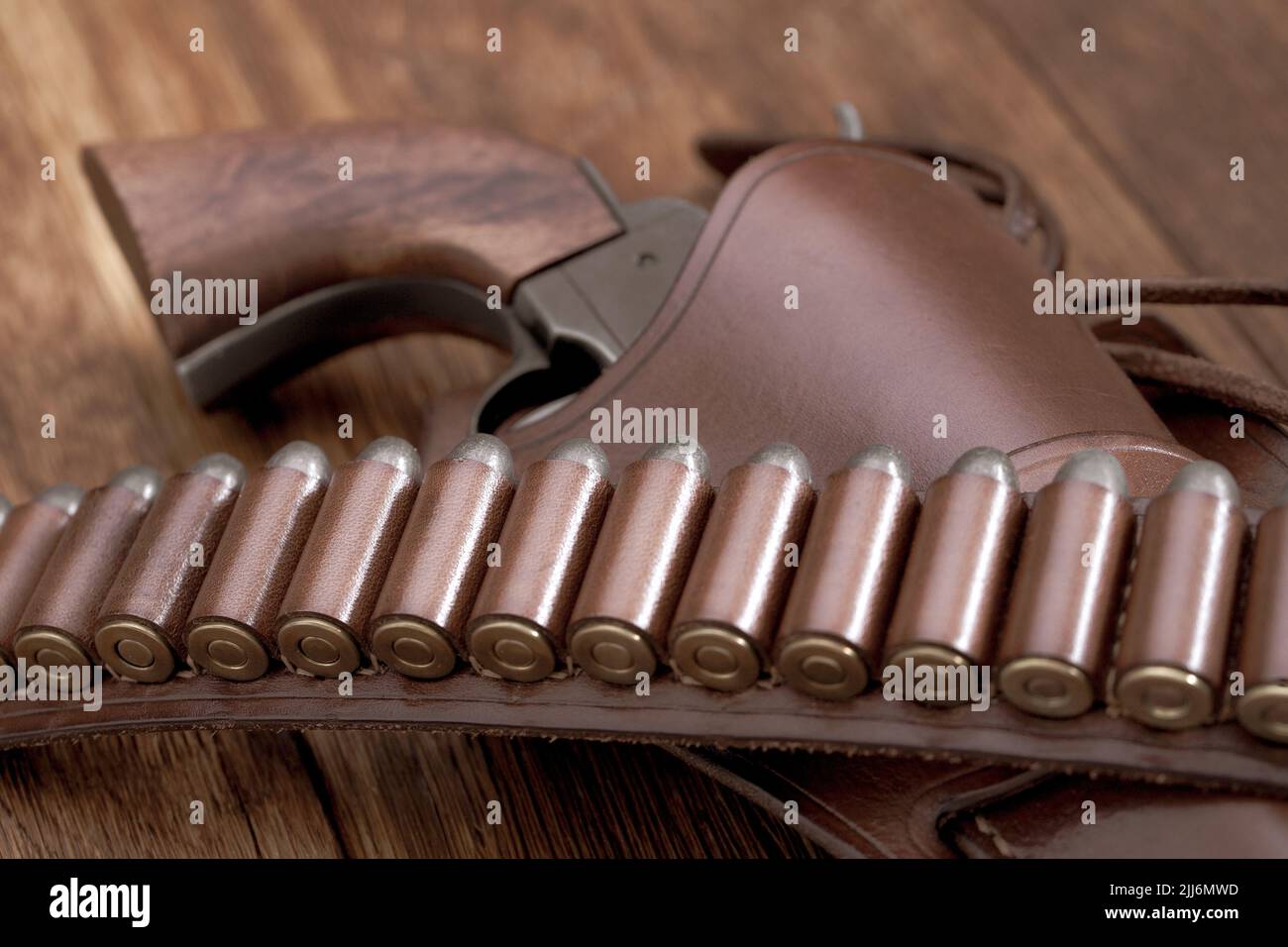 Old west leather gun belt with ammnunition and revolver in holster on wooden table Stock Photo
