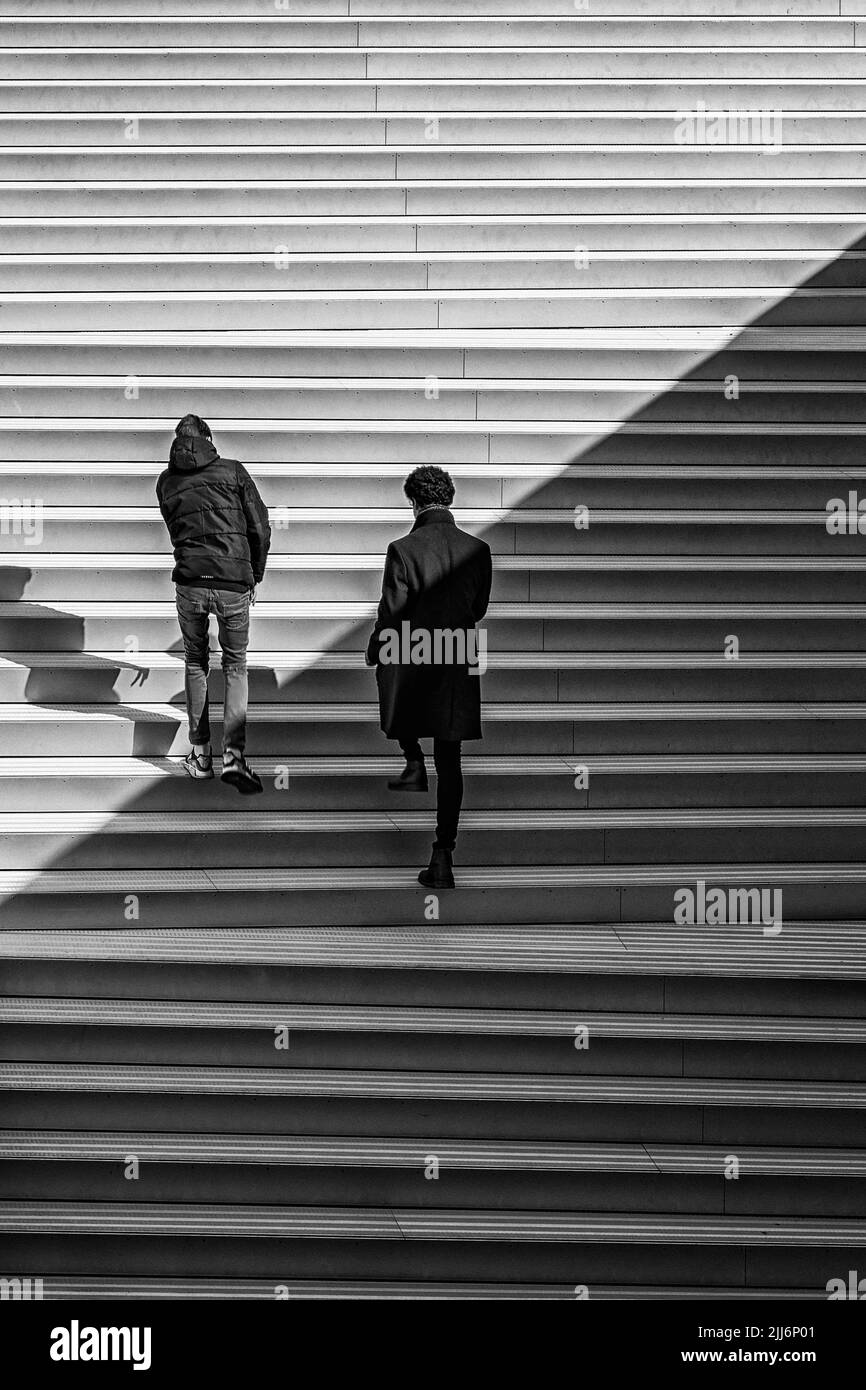 A grayscale back shot of two men climbing an the staircase of MS Maritime Museum in Helsingor, Denmark Stock Photo