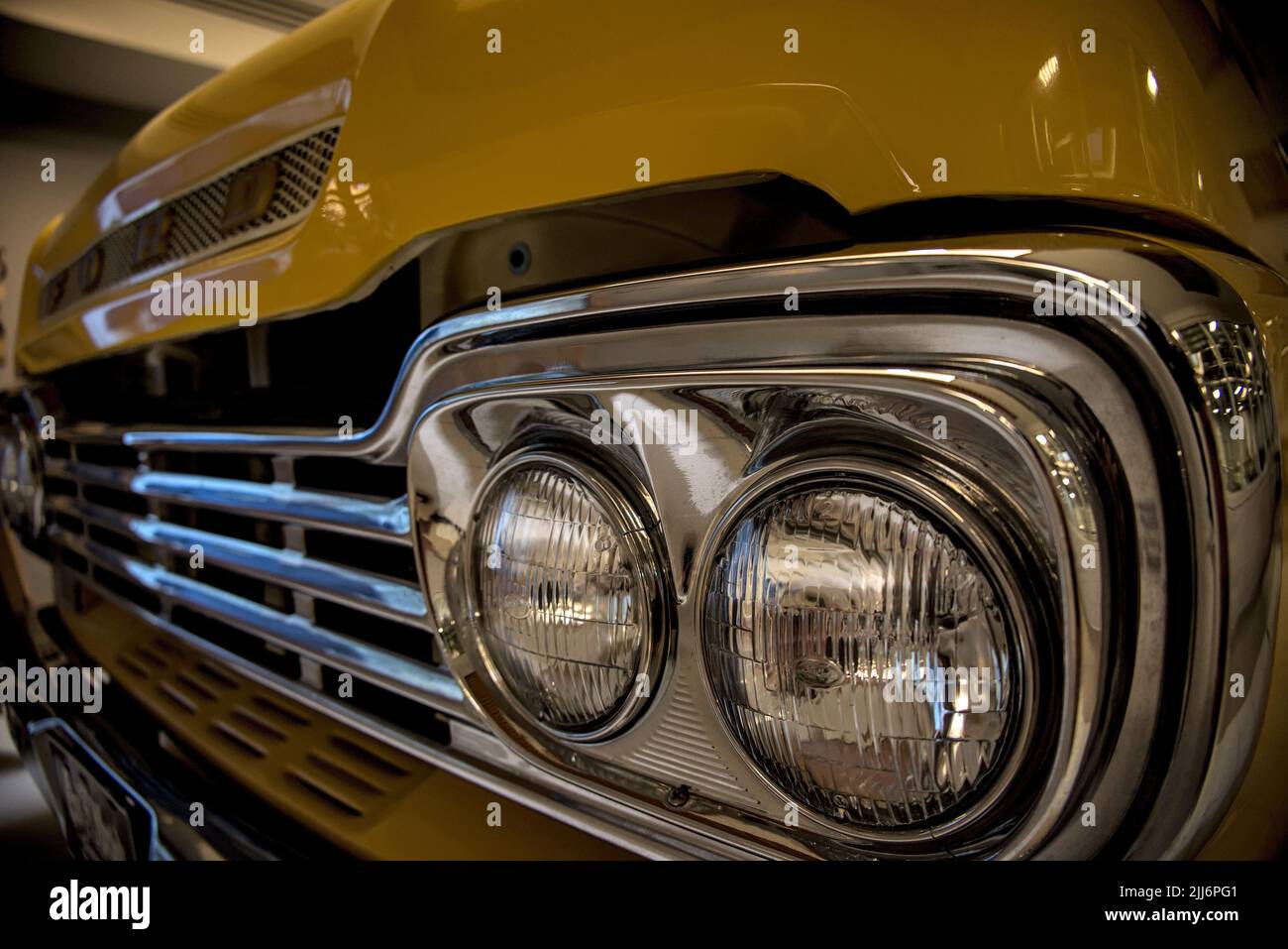A closeup shot of the front grill of a classic yellow ford truck Stock Photo