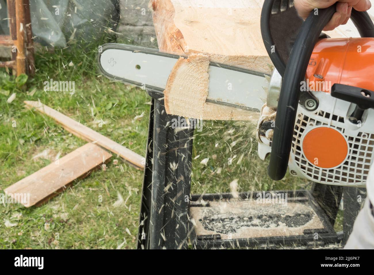 A construction worker cutting boards with a chainsaw in construction