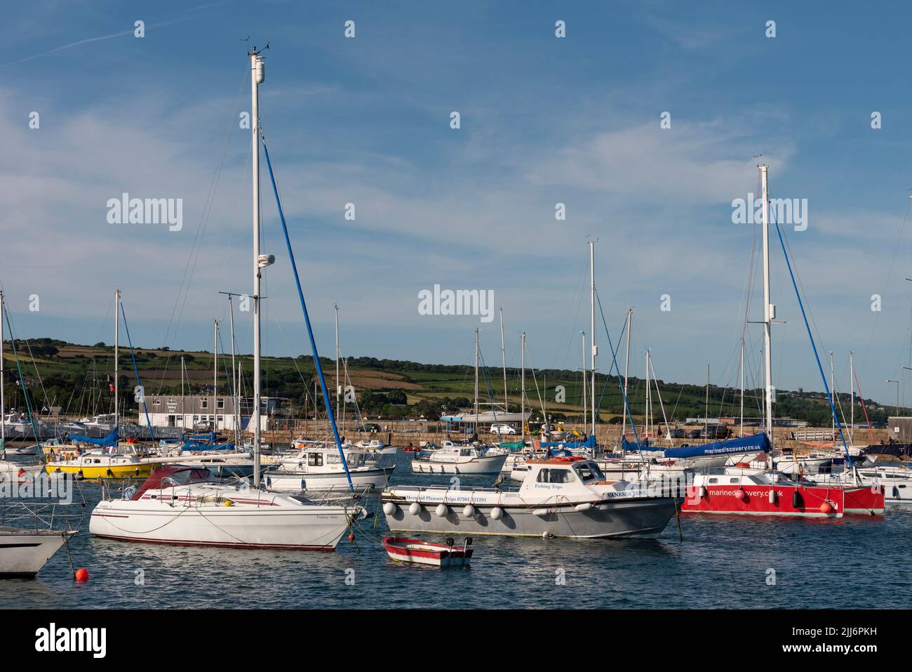 Penzance, Cornwall, England, UK. 2022.  Yachts and day boats on berths with a backdrop of Penzance sailing club hq. Stock Photo