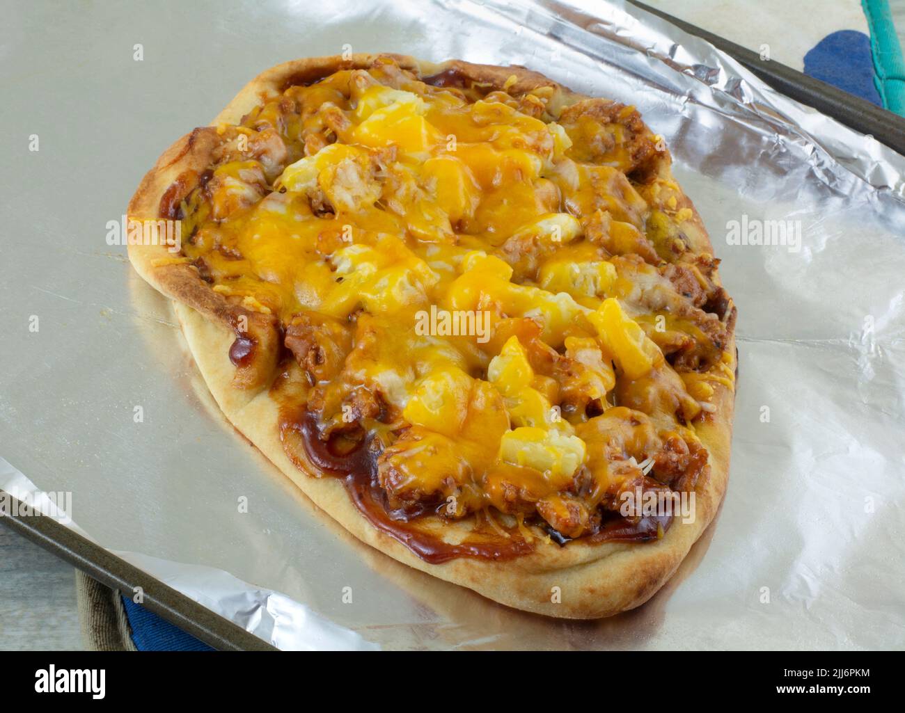 Pineapple and pork homemade flatbread pizza with cheese on aluminum