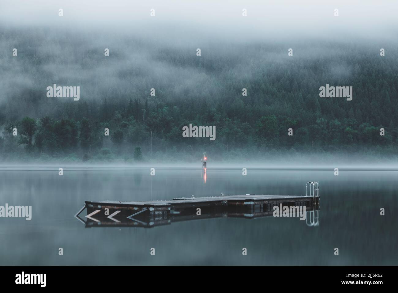 Moody, atmospheric evening fog over floating doch and wharf on scenic Kootenay Lake in Nelson, BC, Canada. Stock Photo