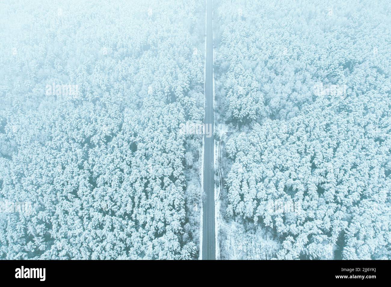 Aerial view of highway road through snow forest landscape in winter. Top view of highway motorway freeway from high attitude. Trip and travel concept Stock Photo