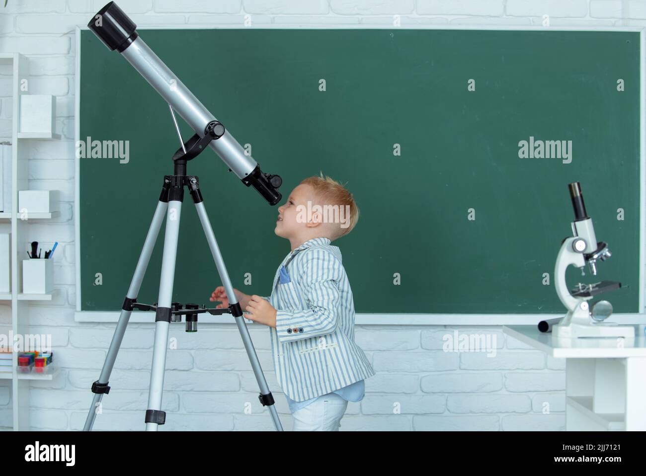School boy with telescope learning astronomy lesson at school Stock