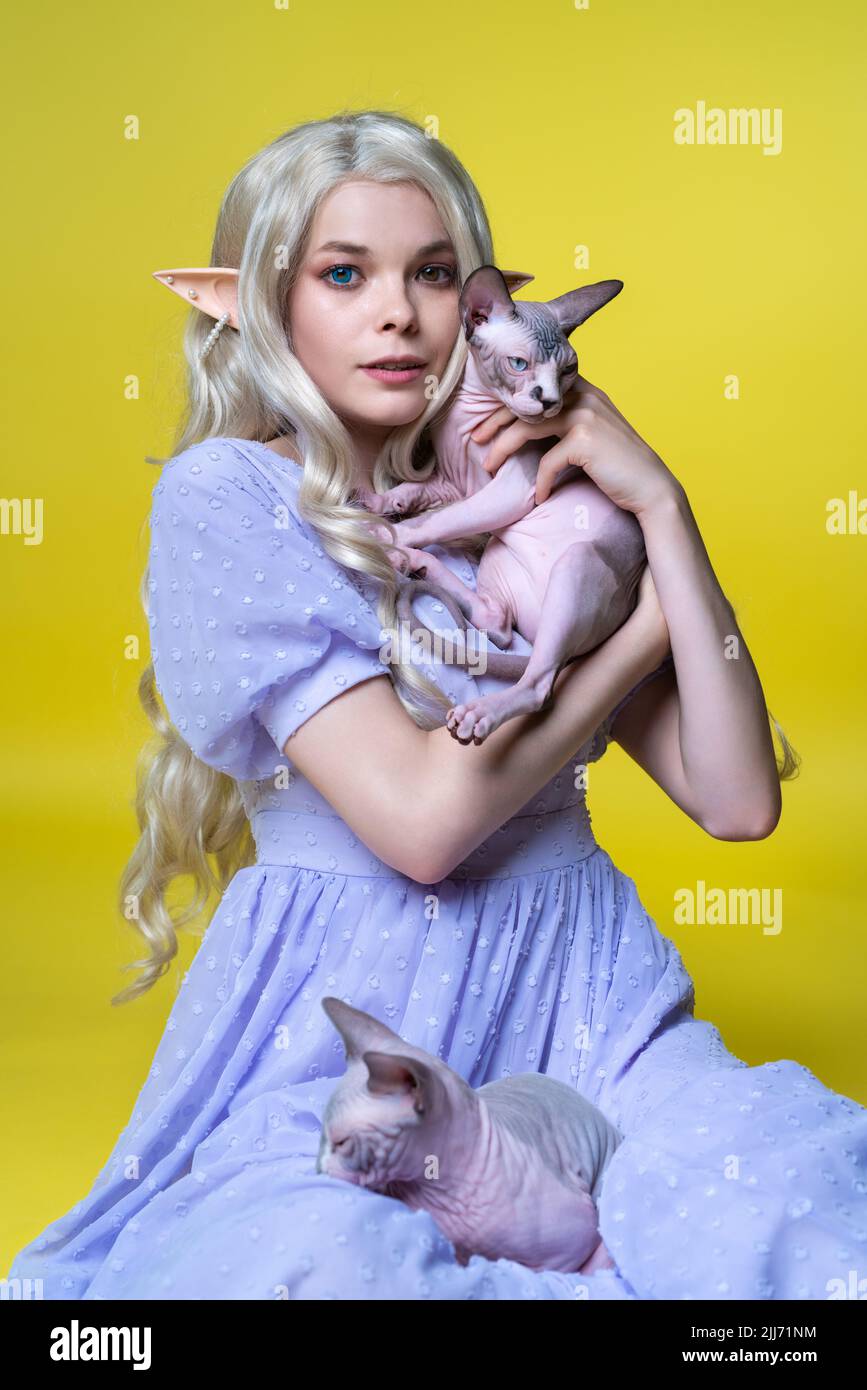 Young female cosplay elf in blue dress sitting with two beloved