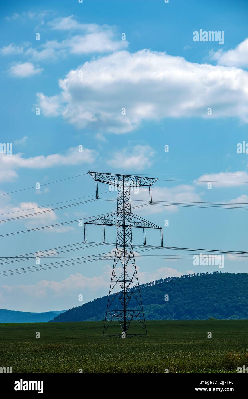 High voltage lines and power pylons in a green landscape on a sunny day ...