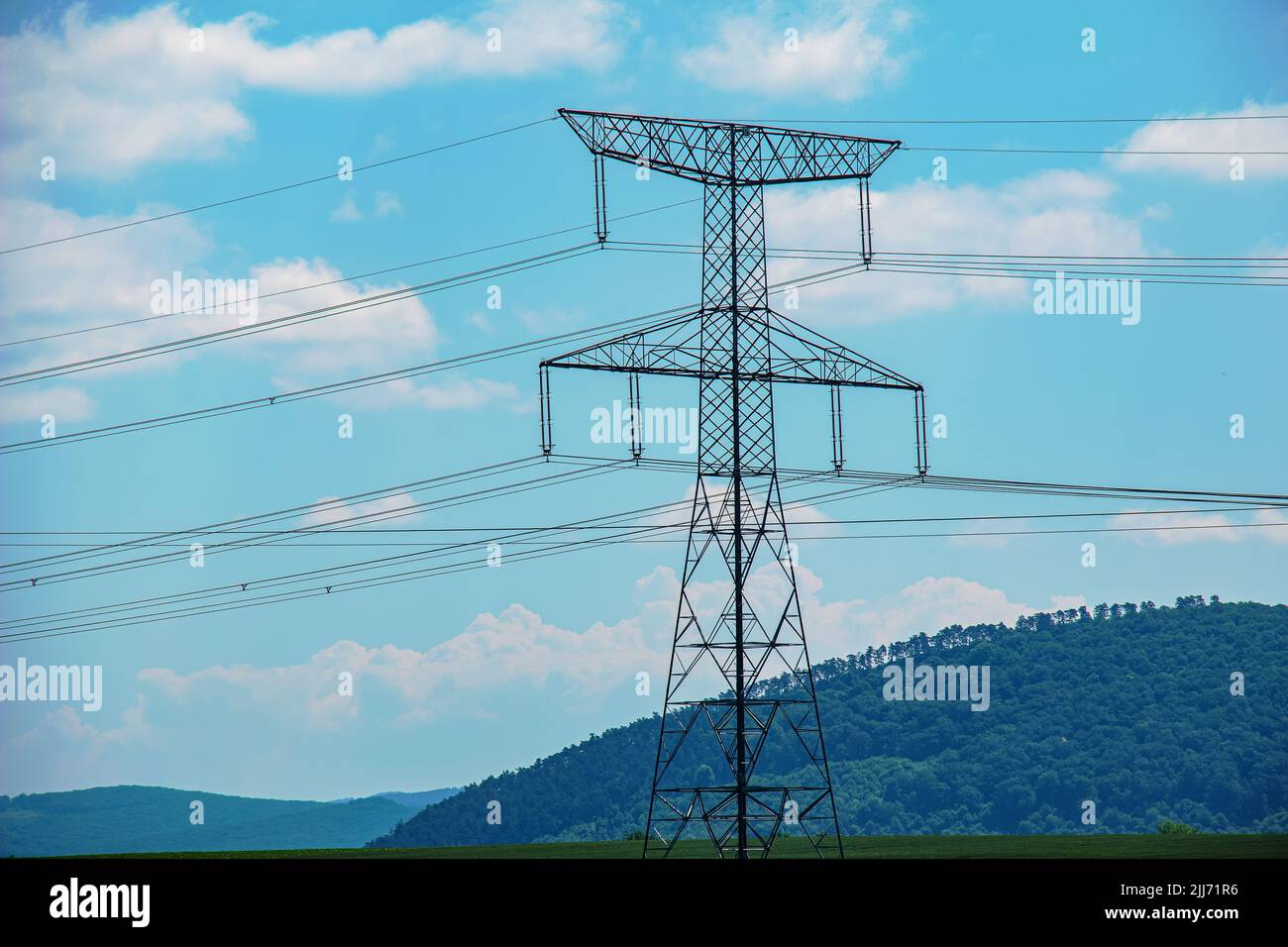 High voltage lines and power pylons in a green landscape on a sunny day ...