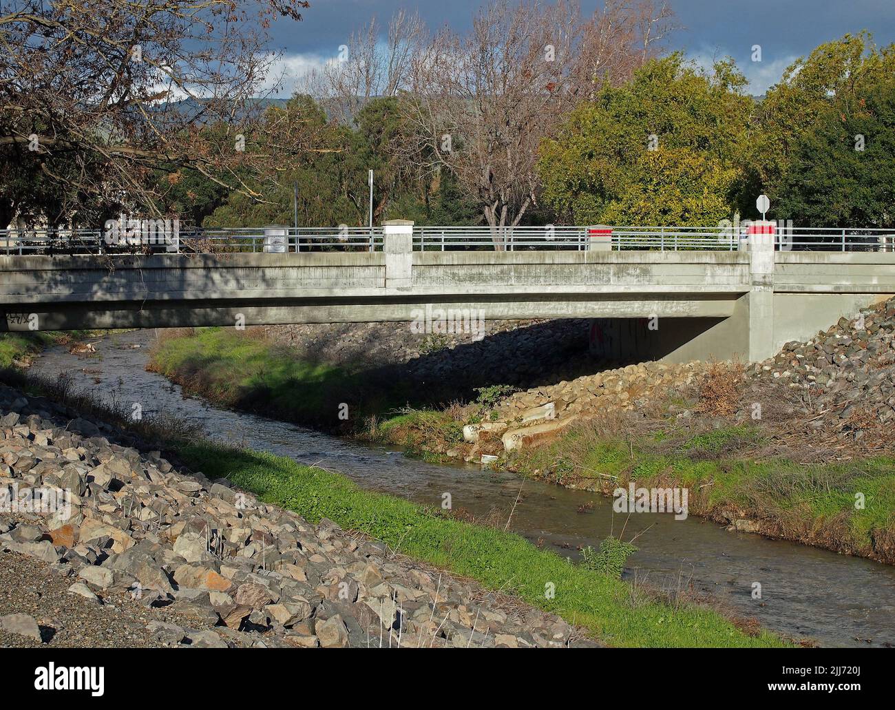 seasonal Dry Creek after a heavy winter rain storm water flowing under the Arizona Street Bridge to the Alameda Creek in Union City, California Stock Photo