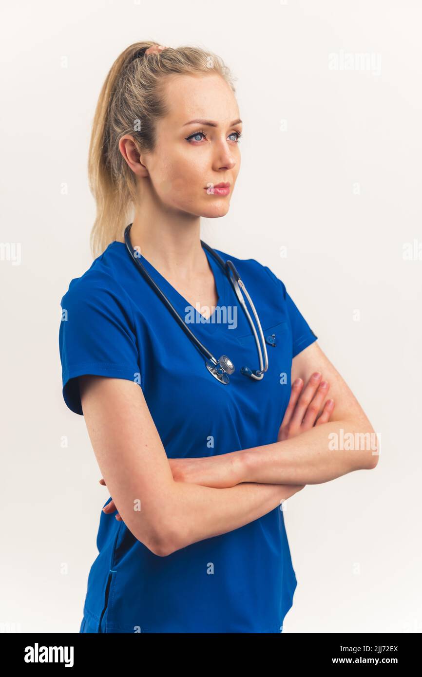 Modern heroes concept. Medical healthcare caucasian female worker in dark blue uniform and stethoscope with crossed arms, standing with a confidence on her face. Vertical studio isolated shot copy space over white background. High quality photo Stock Photo