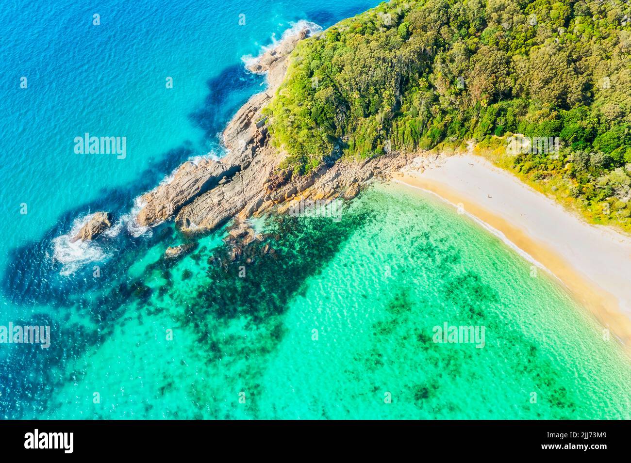 Shelly beach with pristine clean emerald tropical water and white sand on pacific coast of Australia at Elizabeth beach bay. Stock Photo