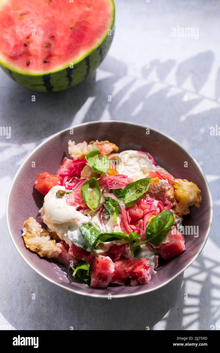 Summer salad with watermelon, buratta, basil and pickled onions Stock Photo